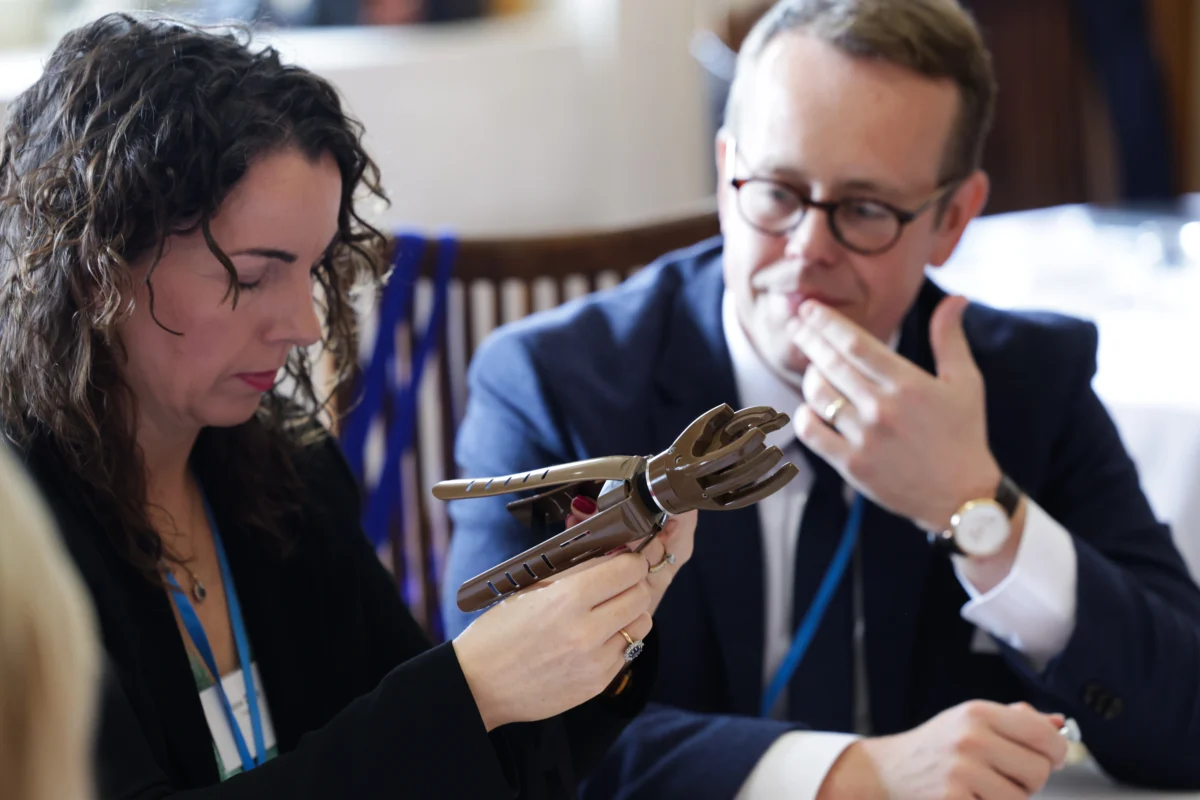 GAH COD Sept 2024 02 Two people examining an artifact at a business meeting table